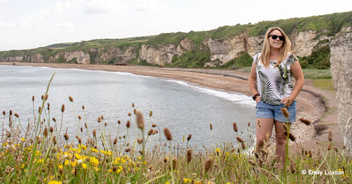 Woman stood smiling at camera on top of cliffs at Blast Beach, County Durham.